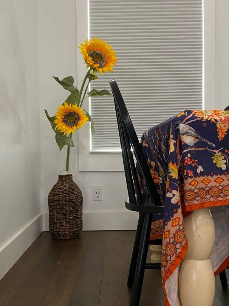 Affordable fall decor tip: sunflowers + a fall-themed table cloth add a nice pop of yellow + orange to a navy-and-white dining area. 